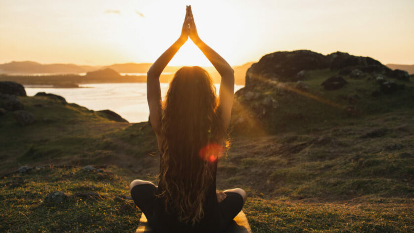 une femme sur la plage en posture de yoga en plein introspection pour mieux se connaitre