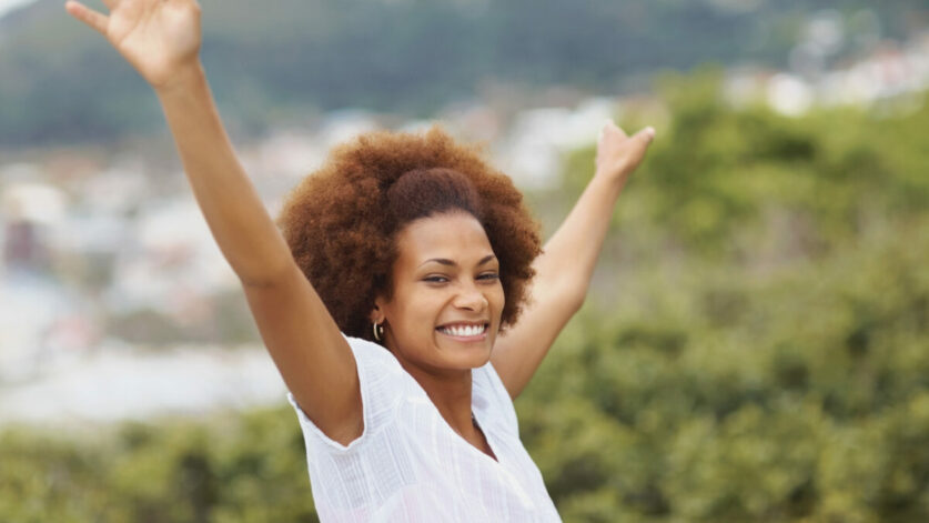 une femme lache prise les bras levés en souriant