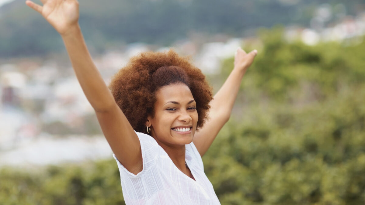 une femme lache prise les bras levés en souriant