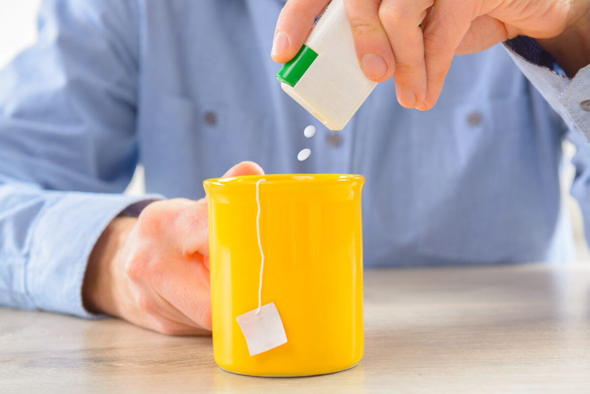 un homme met des édulcorants dans son café