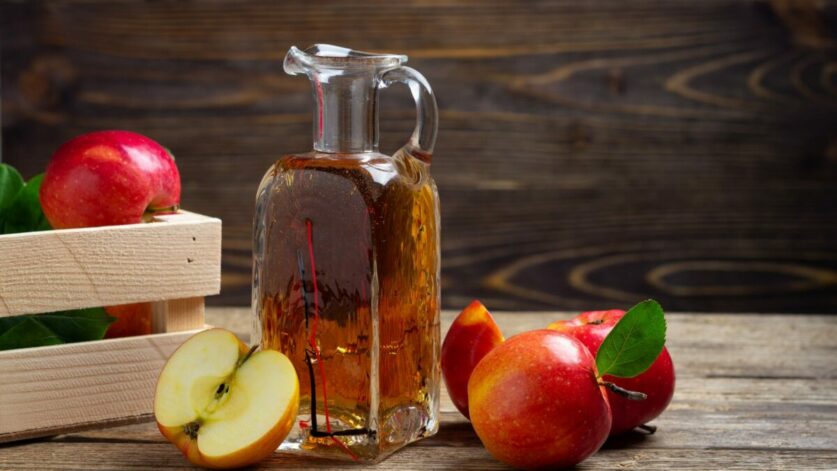 une bouteille de vinaigre de cidre et des pommes