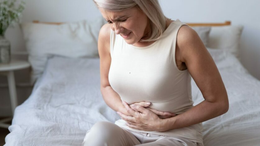 une femme atteinte du syndrome génito-urinaire assise sur son lit