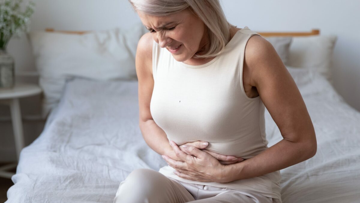 une femme atteinte du syndrome génito-urinaire assise sur son lit